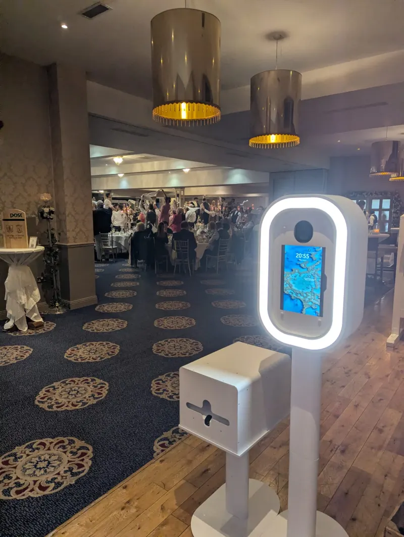 Open air photo booth setup at wedding venue with guests in background