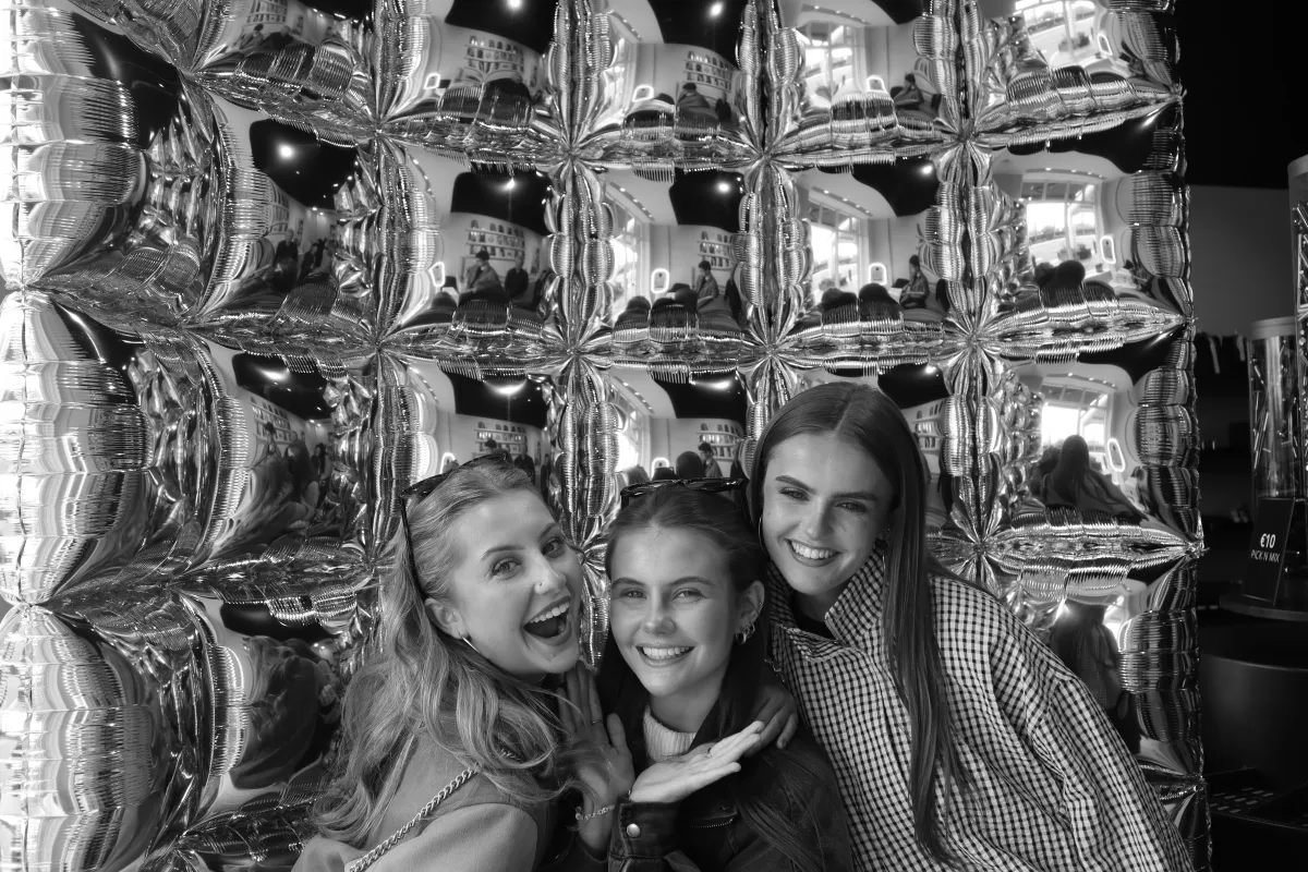Guests at a glamorous grand opening event with silver balloon backdrop