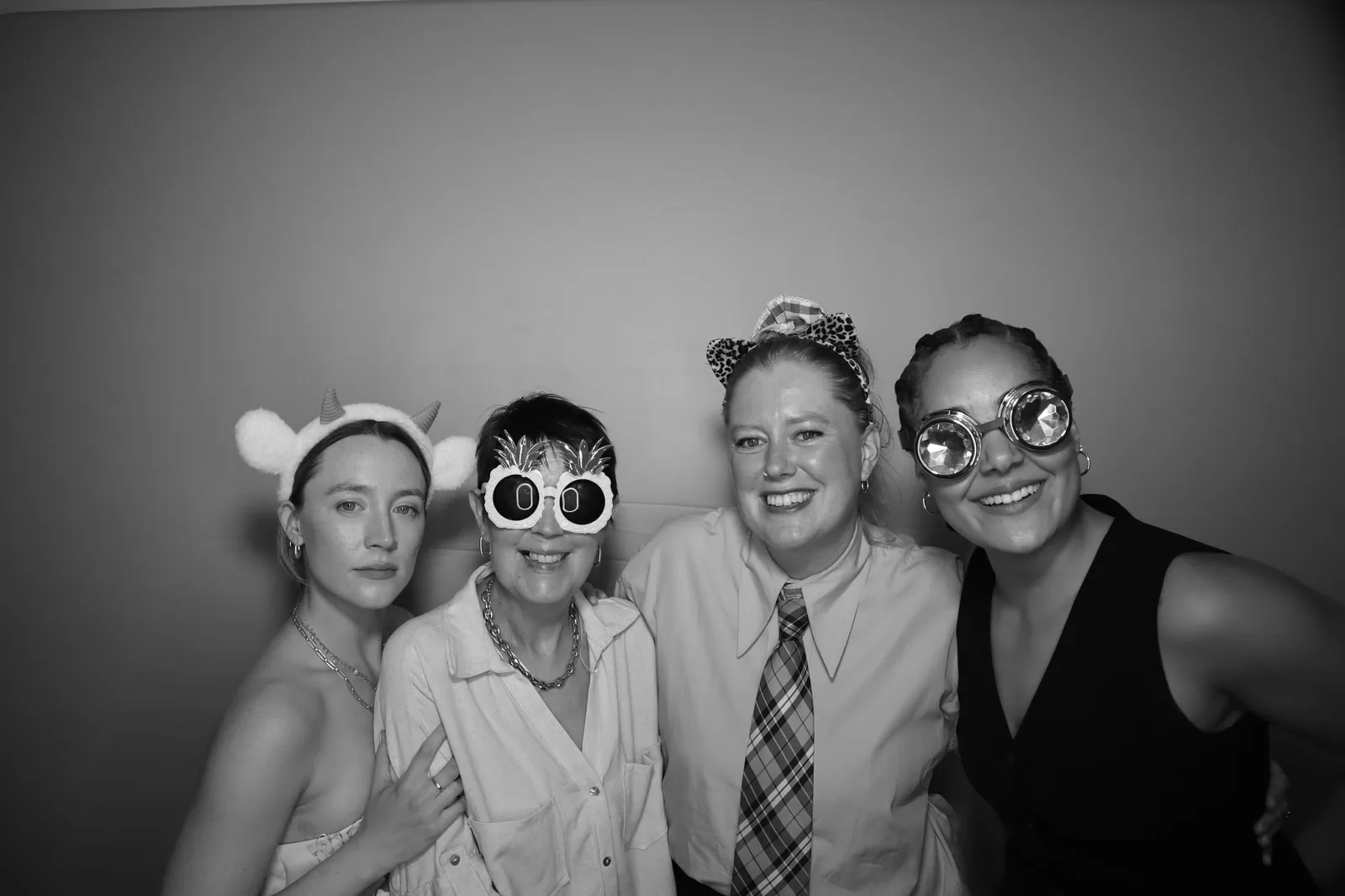 Four wedding guests posing with props at a Photobooth Guys selfie mirror at an Irish wedding, black-and-white print style